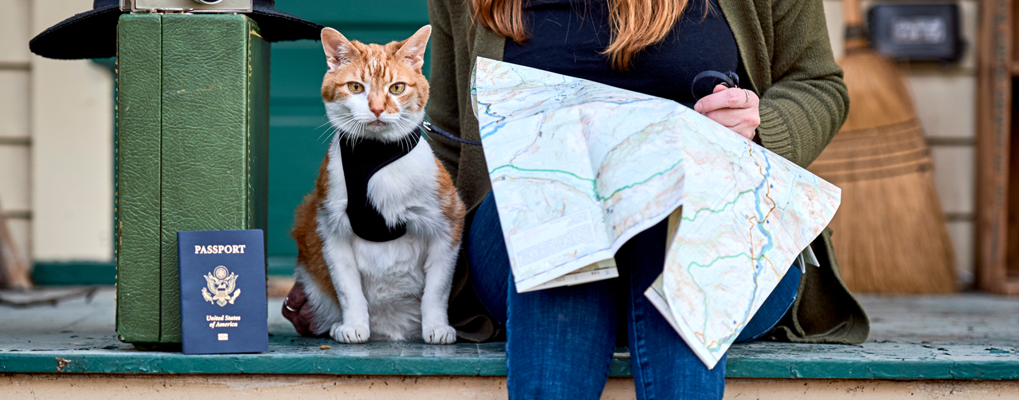 Owner consults a map, with her cat leased next to her, while traveling