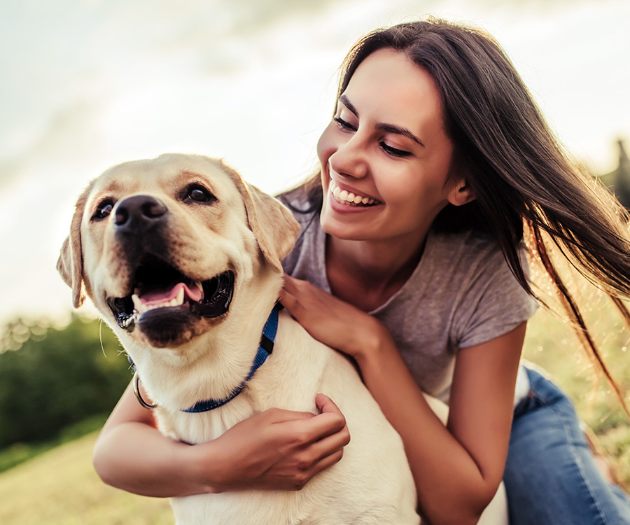 Young woman playing outdoors with dog labrador retriever is one example of how a dog can benefit your health.