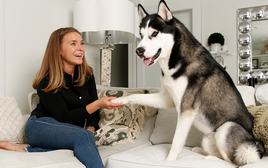 Woman holding paw of dog washed with Hartz True Coat Thick Coat dog deshedding shampoo.